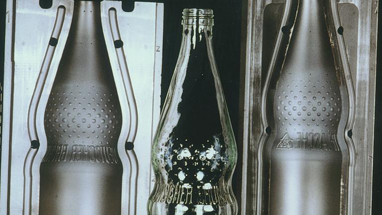Eine Glasperlenflasche zwichen den beiden Hälften ihrer Gussform