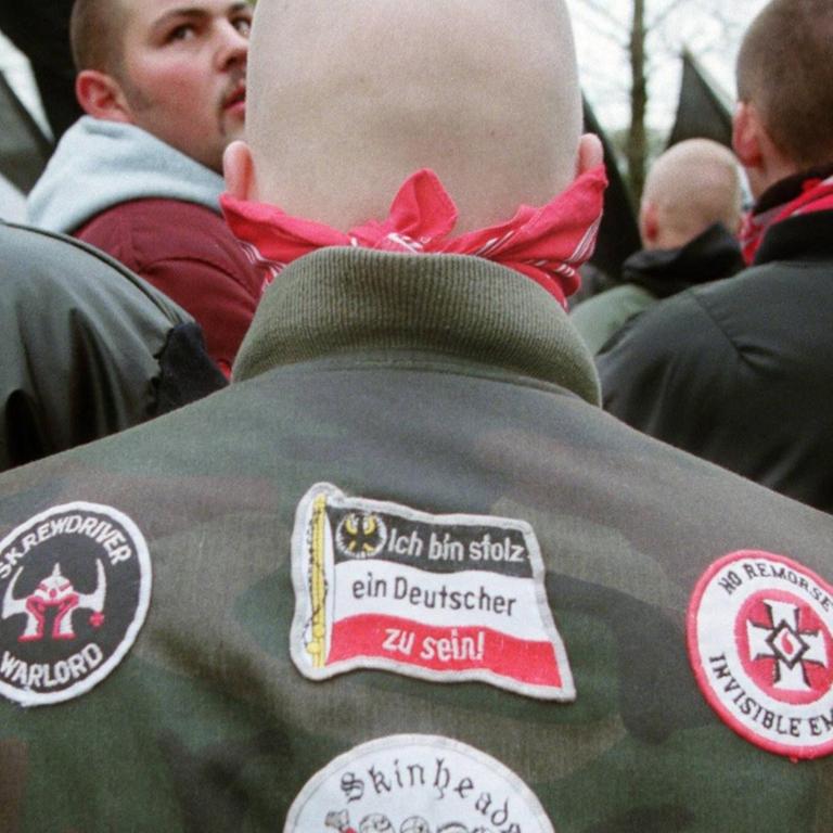 Skinhead von hinten bei einer NPD-Kundgebung. Auf einem Aufnäher steht: "Ich bin stolz ein Deutscher zu sein." 