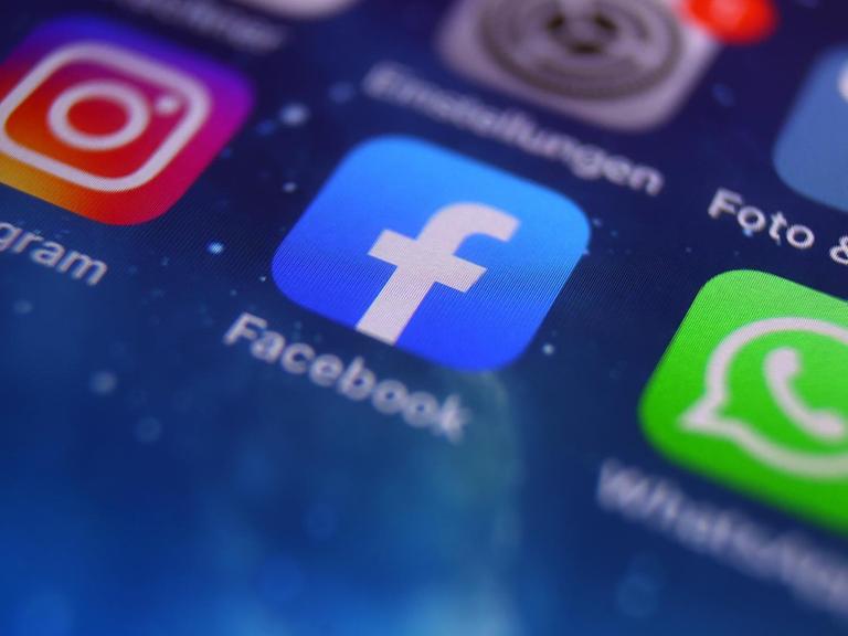 Auf dem Bildschirm eines Smartphones sind die Icons von Instagram, Facebook und WhatsApp zu sehen.