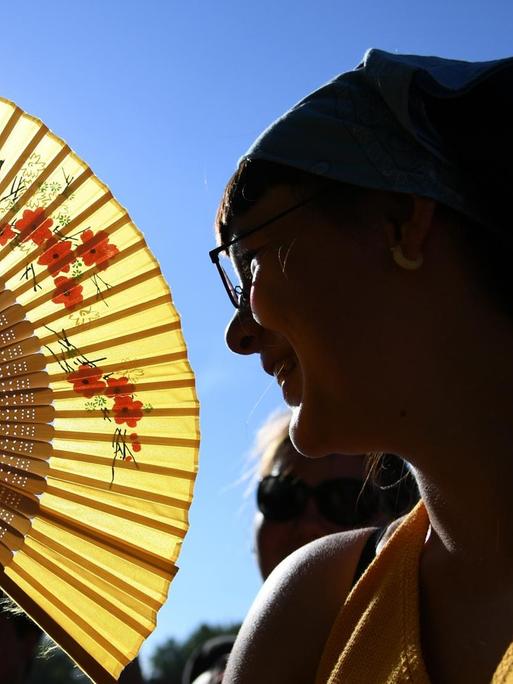 Das Bild zeigt eine Frau, die sich im Sommer kühle Luft zufächelt.