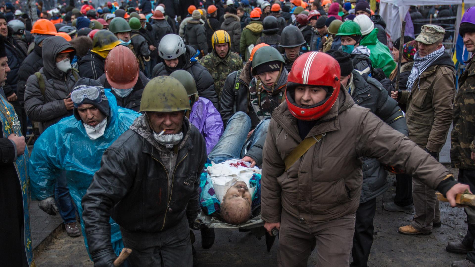 Aktivisten tragen im Februar 2014 einen Verletzten vom Maidan.
