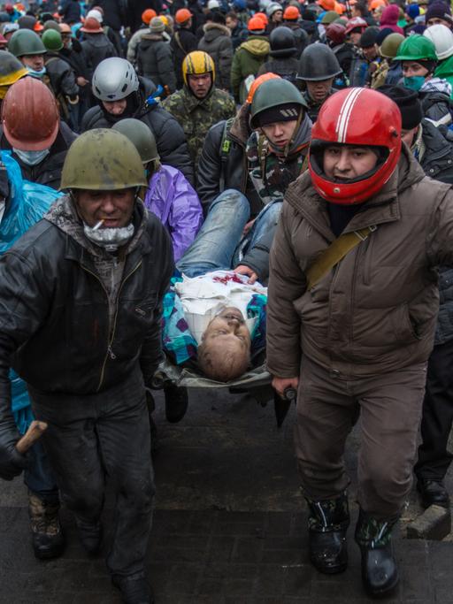 Aktivisten tragen einen Verletzten vom Maidan.