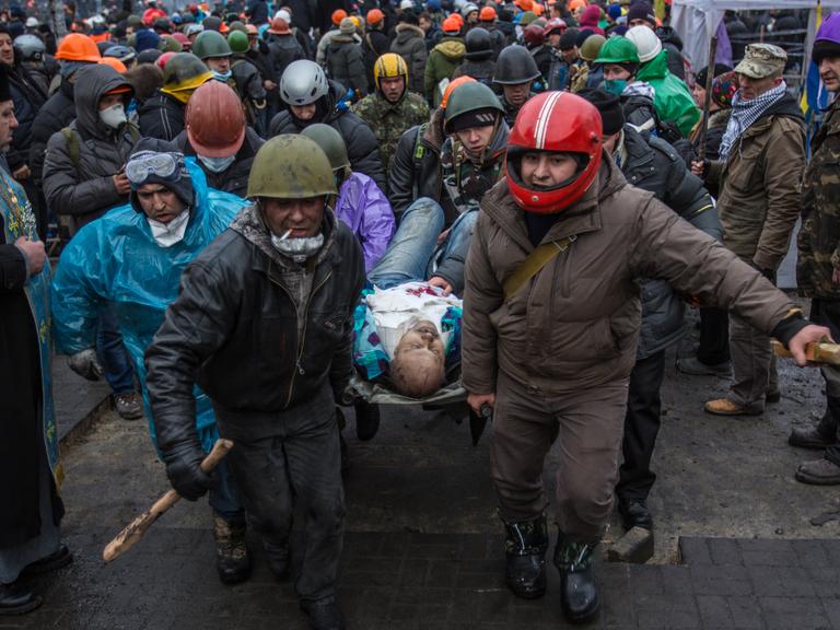 Aktivisten tragen einen Verletzten vom Maidan.