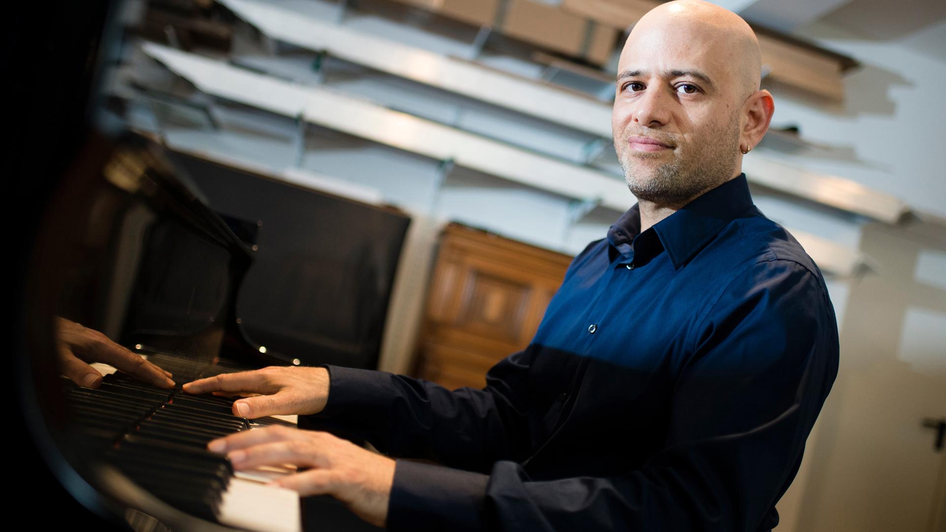 Der in Israel geborene Pianist Ohad Ben-Ari posiert am 29.07.2015 im Geschäft "Markus Fischinger Klavierbau" in Berlin an einem Flügel. Ben-Ari ist einer von geschätzt 11.000 jüdischen Israelis, die sich in Berlin niedergelassen haben.