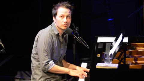 Marco Tschirpke sitzt am Klavier, spielt und schaut Richtung Publikum