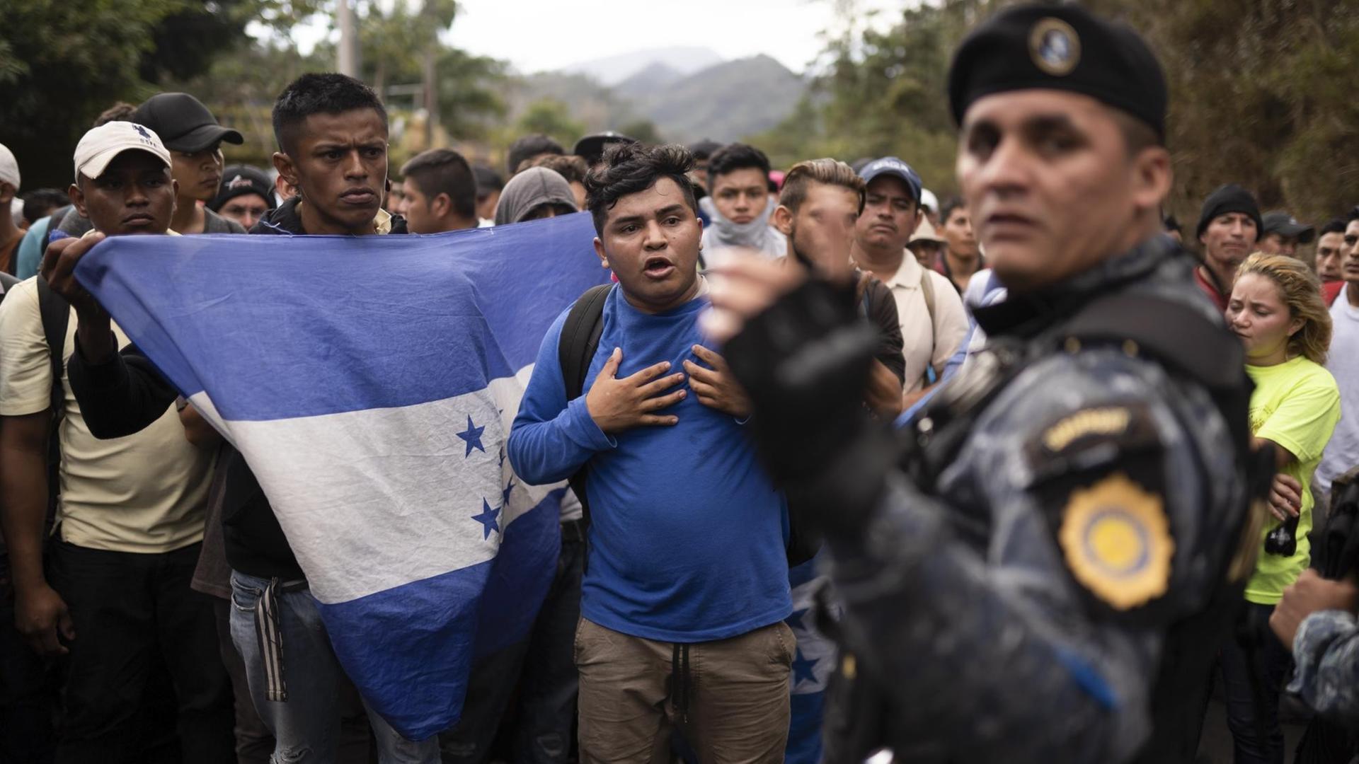 Flüchtlinge aus Honduras werden an der Grenze zu Guatemala vom Grenzschutz aufgehalten. Einer von ihnen schwenkt die honduranische Flagge.