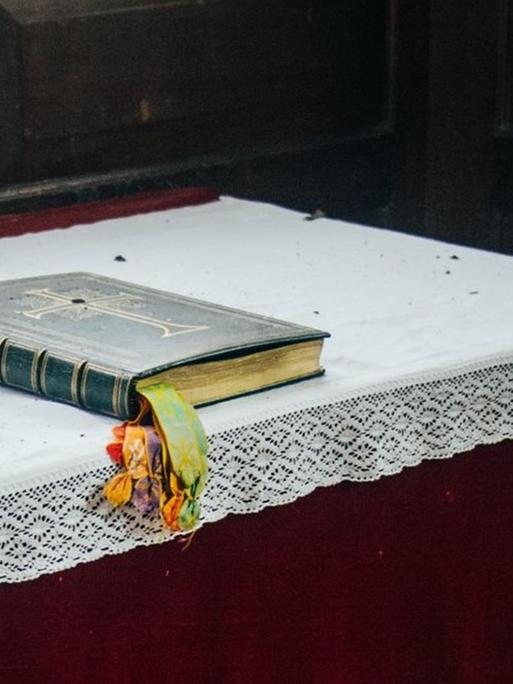 Ein Gebetbuch liegt auf einem Altartisch in einer Kirche.