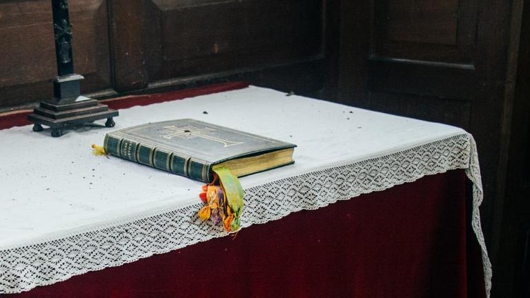 Ein Gebetbuch liegt auf einem Altartisch in einer Kirche.