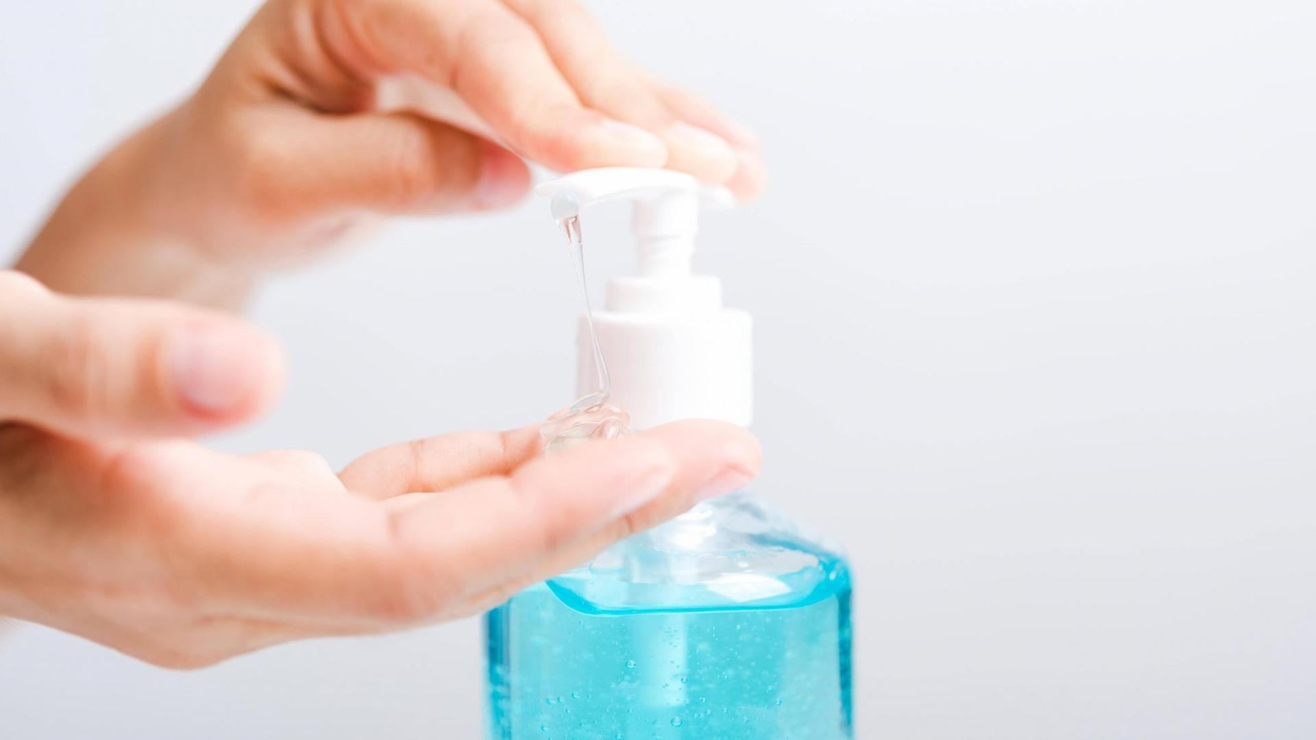 Eine Frau desinfiziert sich die Hände - Nahaufnahme der Hände mit einer Flasche Desinfektionsmittel.