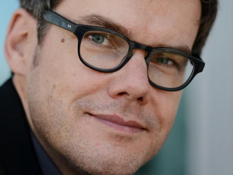 Porträt des Journalisten Ralph Bollmann, aufgenommen am 10.10.2013 auf der Frankfurter Buchmesse. Er trägt ein dunkles Jackett, graues Hemd und eine dunkle Brille.