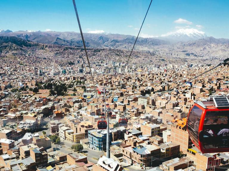 Über der Kulisse von La Paz schwebt eine rote Seilbahngondel.