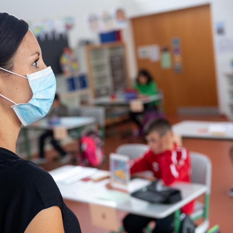 Eine Lehrerin mit Mund- und Nasenschutz steht in einer Grundschule. Foto: Sebastian Gollnow/dpa | Verwendung weltweit