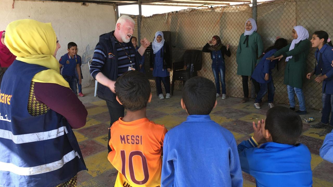 CARE-Helfer Khaled sing mit Jungs und Mädchen Lieder in einem Container in Al Azraq.