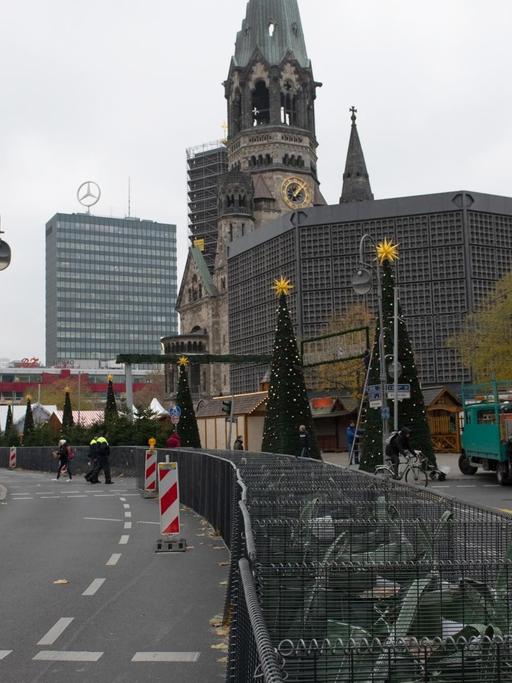 Eisenkörbe mit Sandsäcken gefüllt stehen am Weihnachtsmarkt am Breitscheidplatz. Der Berliner Weihnachtsmarkt an der Gedächtniskirche wird zwei Jahre nach dem islamistischen Terroranschlag mit zwölf Todesopfern aufwendig abgeriegelt.