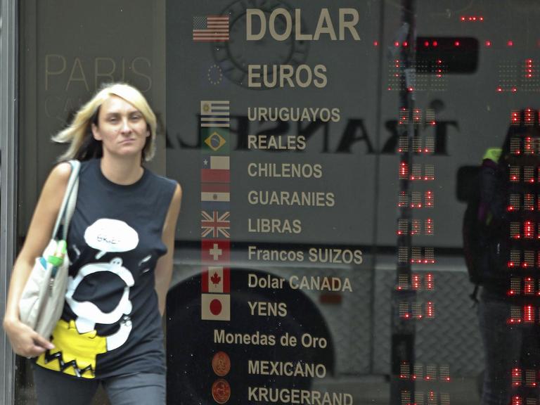 Eine Frau läuft am 24.1.2014 in der argentinischen Hauptstadt Buenos Aires an einer Anzeigetafel mit Währungskursen vorüber.