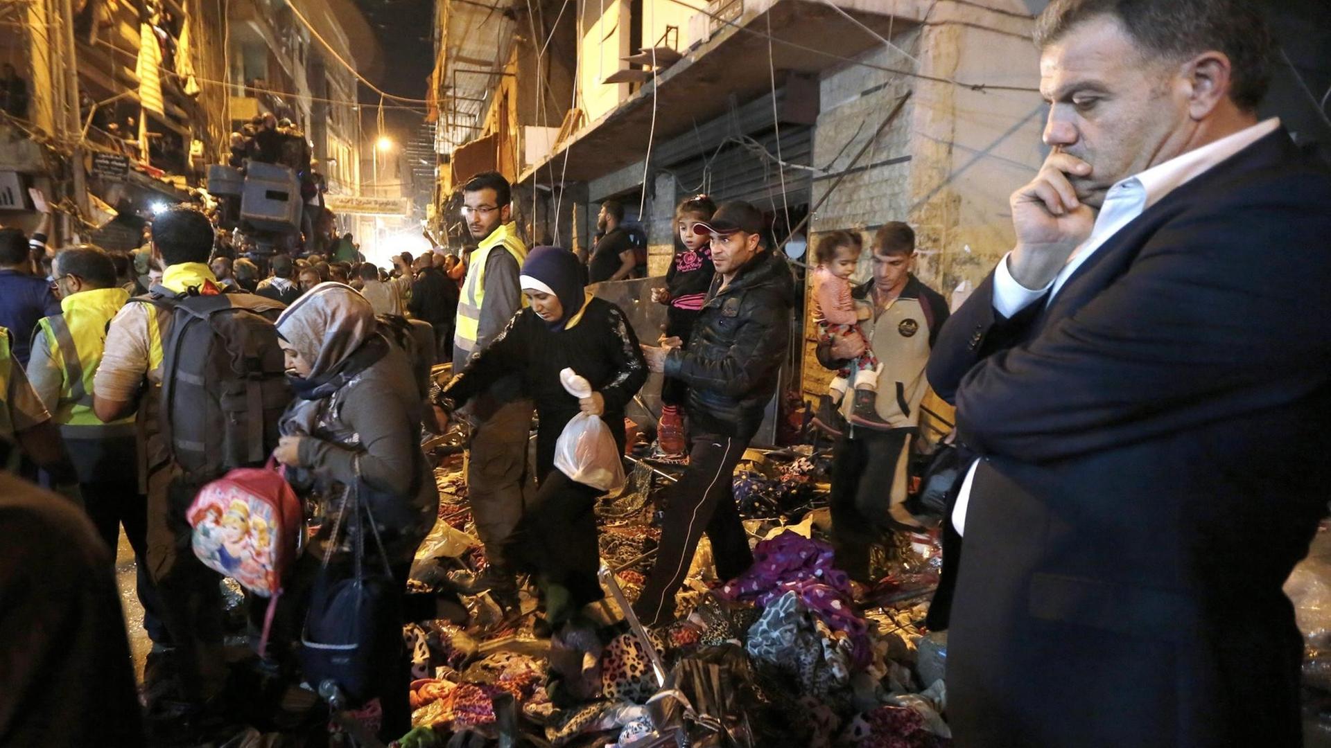 Eine Familie geht über die Trümmer, nachdem sie ihr Haus an der Seite verlassen haben, wo zwei Selbstmordattentäter sich am 12.11.2015 selbst in Bourj al-Barajneh/Südbeirut/Libanon in die Luft gejagt haben.