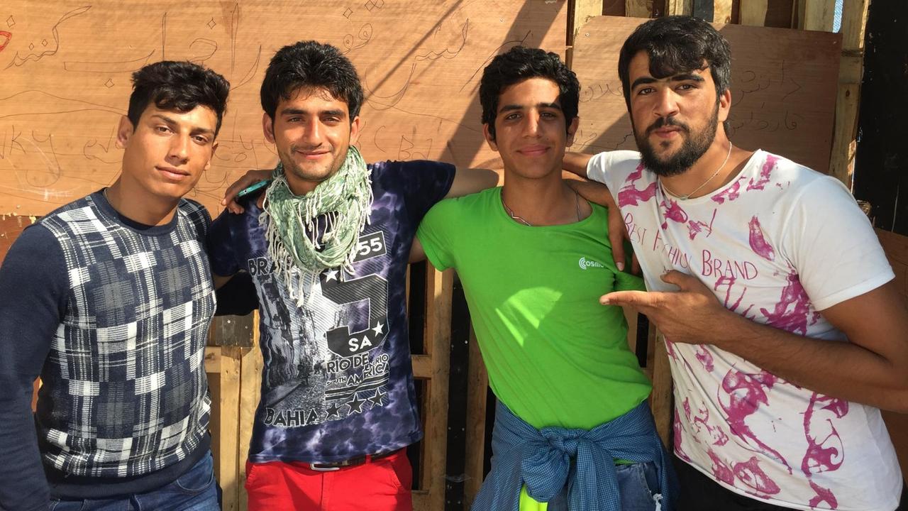 Vier junge Afghanen stehen umarmt nebeneinander und posieren für die Kamera.