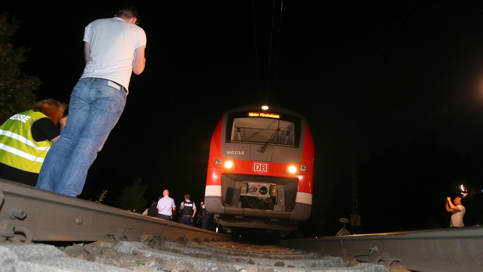Polizisten stehen am 18.07.2016 in Würzburg (Bayern) neben einem Regionalzug. Ein Mann hat in dem Zug Reisende angegriffen und laut Polizei mehrere Menschen lebensgefährlich verletzt. Nach der Attacke wurde der Täter von der Polizei auf der Flucht erschossen.