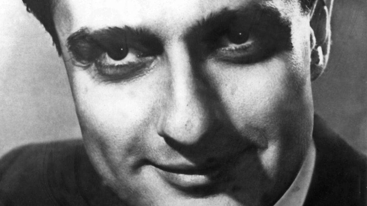 Zeitgenössische Aufnahme des rumänischen Pianisten und Komponisten Dino Lipatti, der mit nach hinten gegeltem Haar in die Kamera lächelt.