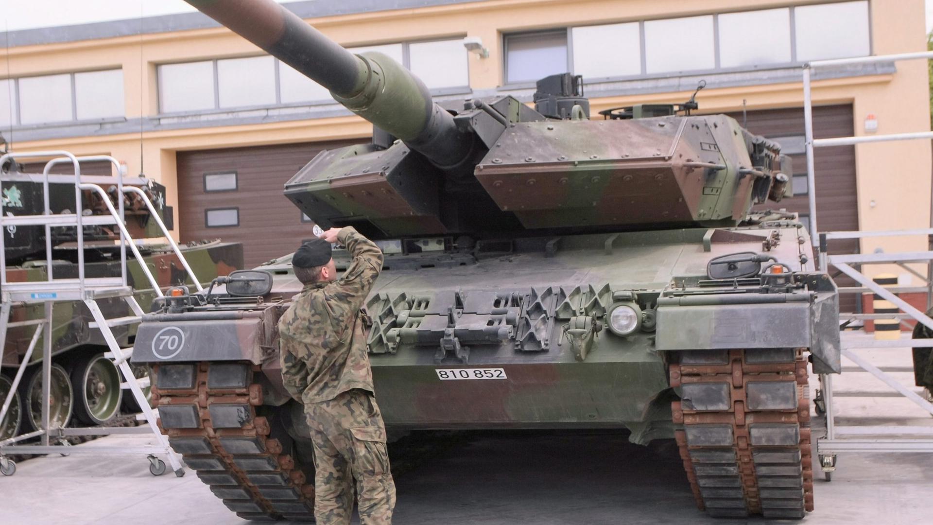 Ein Soldat begutachtet einen deutschen Leopard-Panzer.