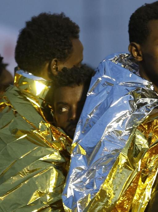 Afrikanische Flüchtlinge auf Sizilien sind in Wärmedecken eingehüllt.