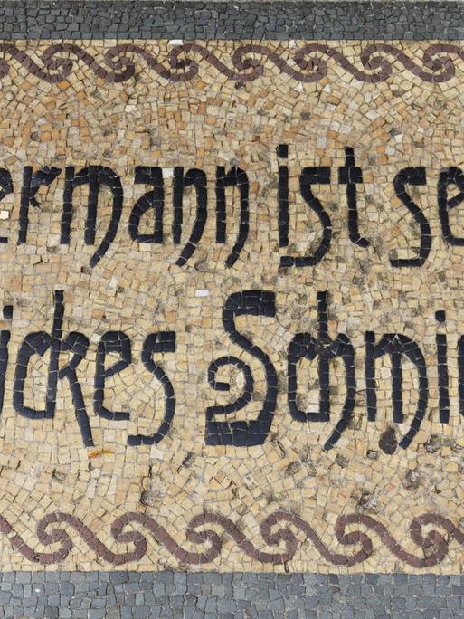 Ein Bodenmosaik in Neuruppin mit dem Sinnspruch "Jedermann ist seines Glückes Schmied"