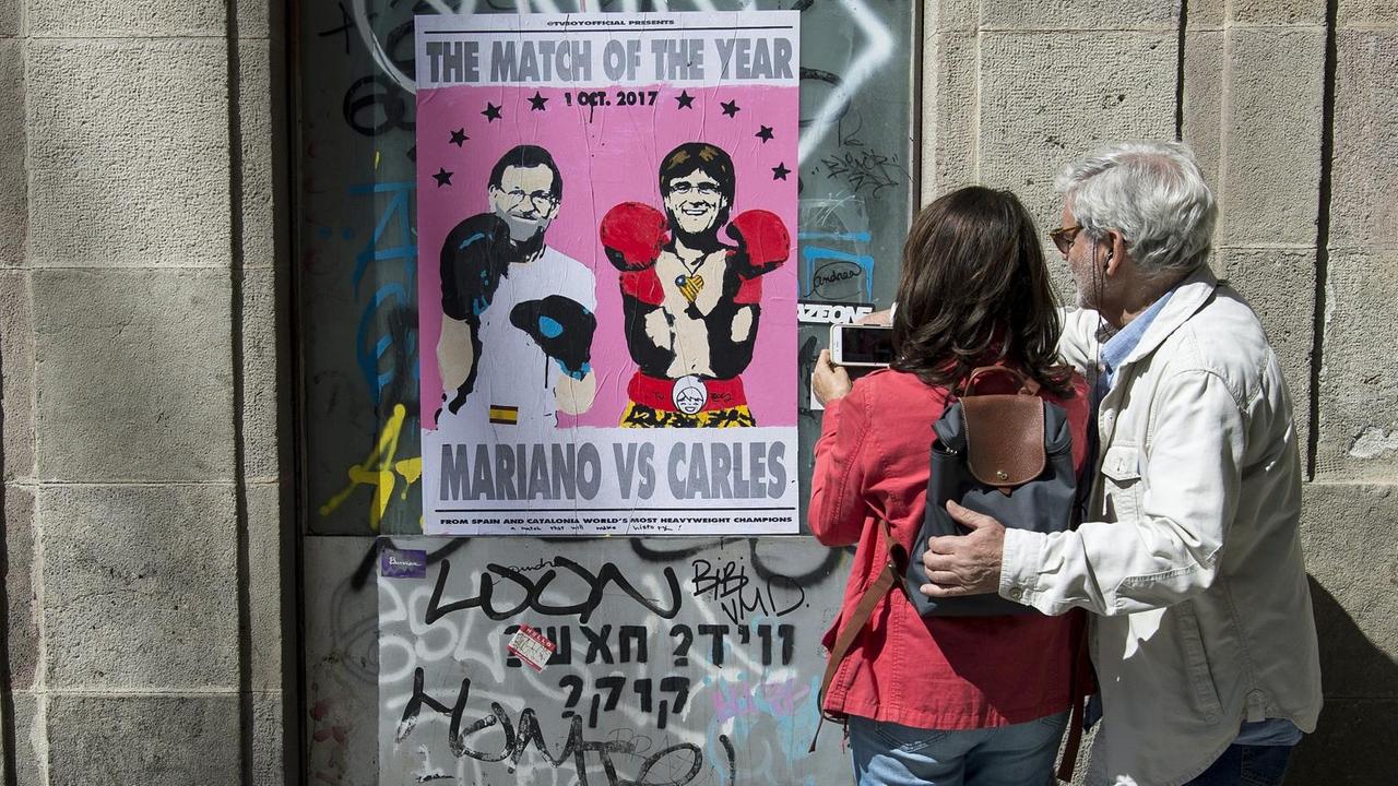 Ein Plakat zeigt Spaniens Ministerpräsident Mariano Rajo und den katalanischen Regionalpräsidenten Carles Puigdemont - mit Boxhandschuhen.