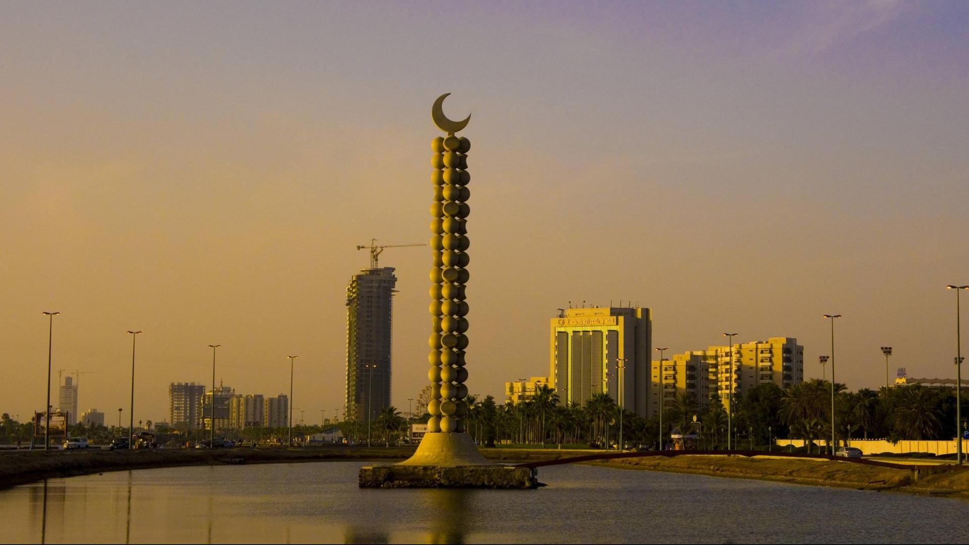Eine Ansicht auf die saudi-arabische Hafenstadt Dschidda. Im Vordergrund ein Monument mit einem Halbmond, im Hintergrund Hochhäuser.
