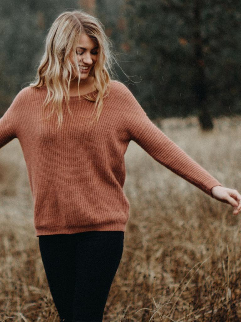 Eine Frau steht lächelnd in der Natur.