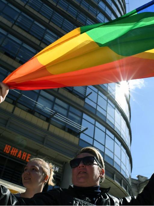 Russische Homosexuelle demonstrieren in Moskau für ihre Rechte. Sie halten bunte Fahnen.