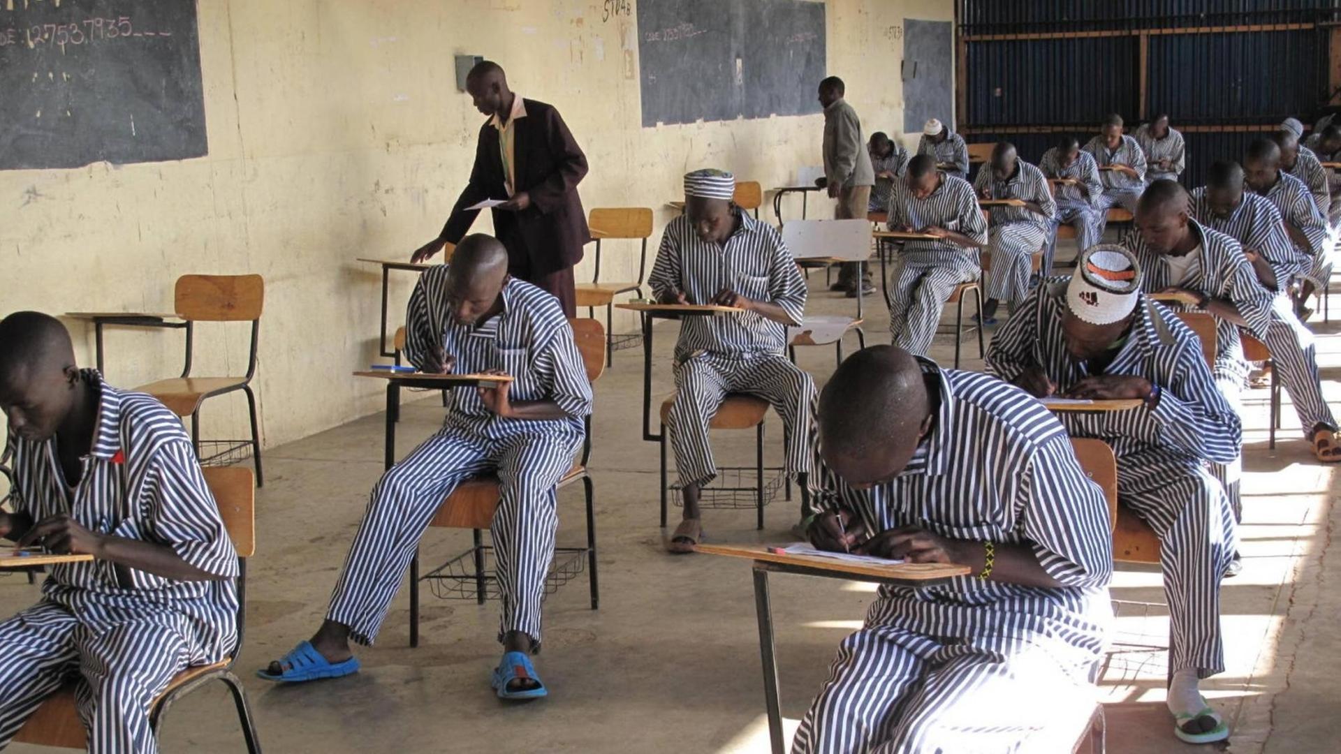 Mehrere Gefängnisinsassen sitzen in einem Schulzimmer in ihre Prüfungsblätter vertieft. Aufgenommen in einem Gefängis im kenianischen Naivasha am 4. November 2014.