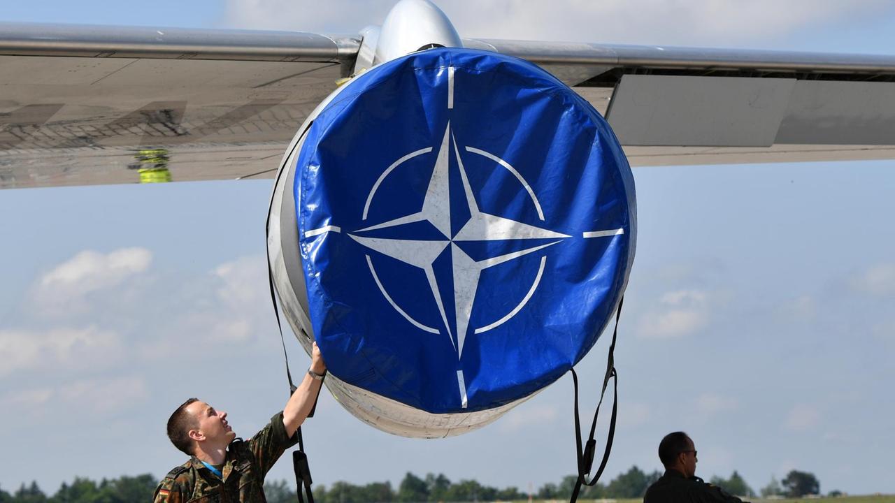 Mechaniker hanitieren in Schönefeld (Brandenburg) auf der Internationalen Luft- und Raumfahrtmesse ILA an einer Schutzhülle mit dem Logo der Nato an einem AWACS Aufklärungsflugzeug