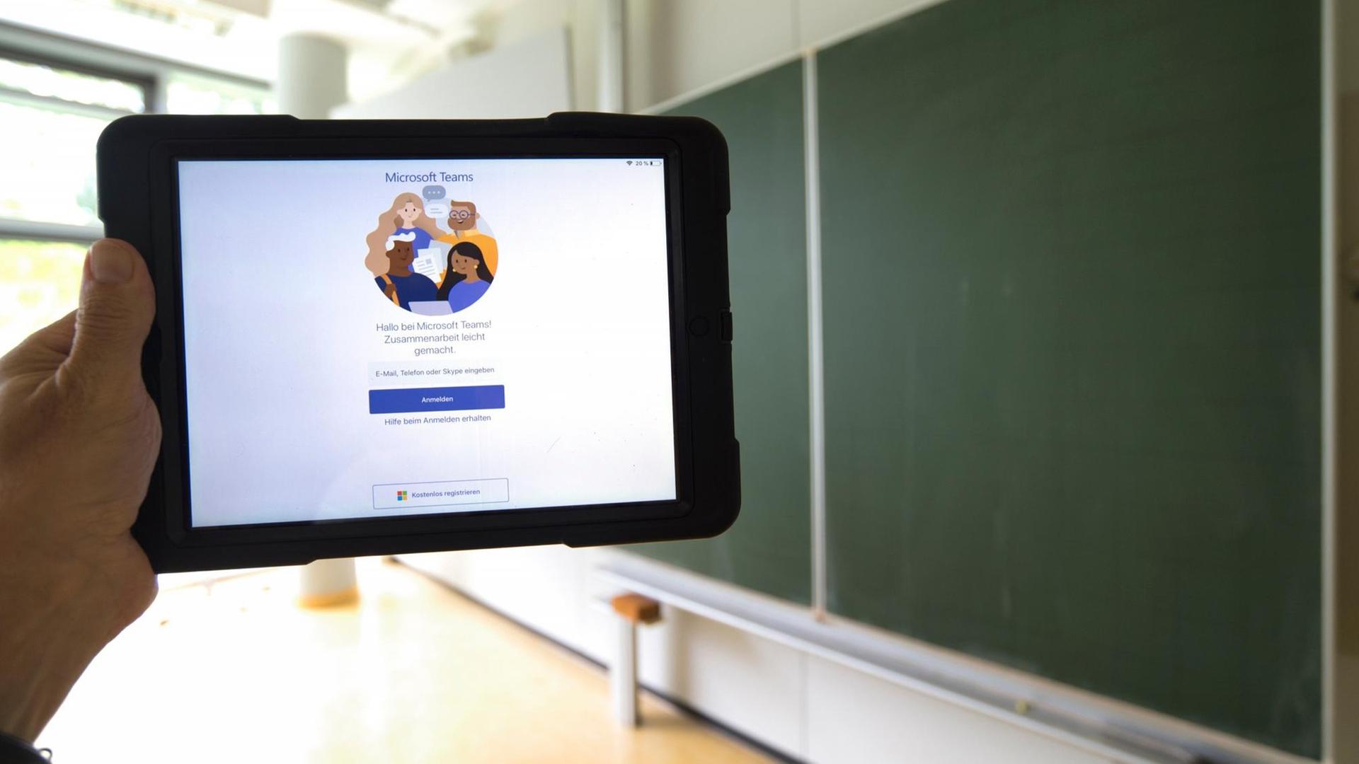 Ein Tablet mit Microsoft Teams vor einer Tafel in einem leeren Klassenzimmer 