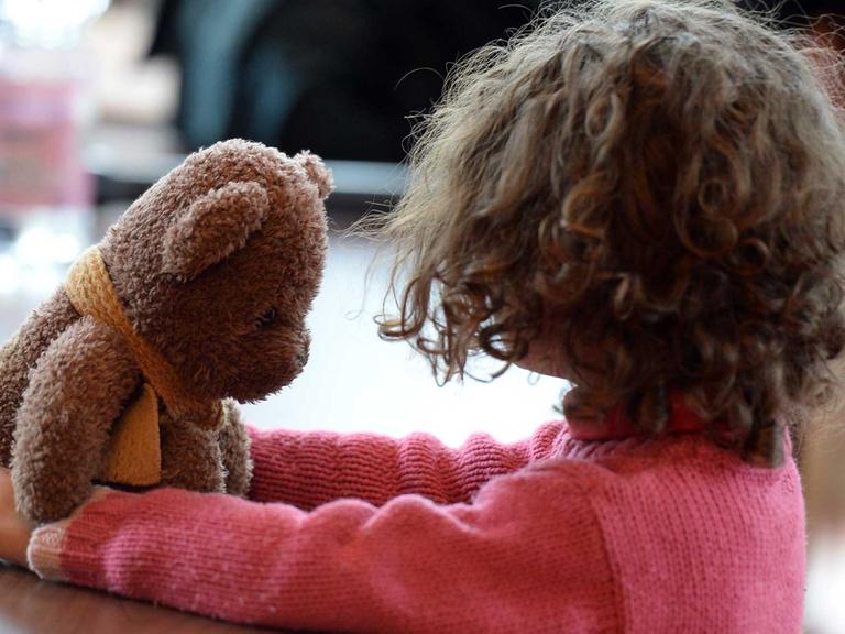 Ein kleines Mädchen spielt am 29.03.2016 in Berlin in einer Notunterkunft für Flüchtlinge mit ihrem Teddy.