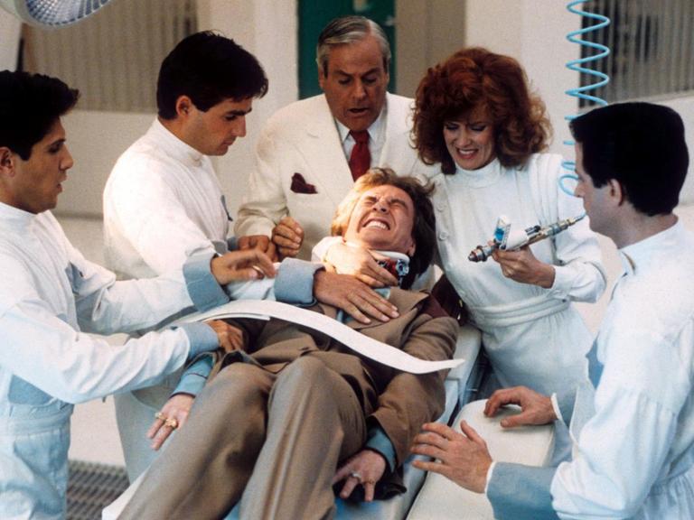 Martin Short liegt in der Filmszene festgezurrt auf einer Bare, umringt von 5 Ärzten mit einer riesigen Spritze.