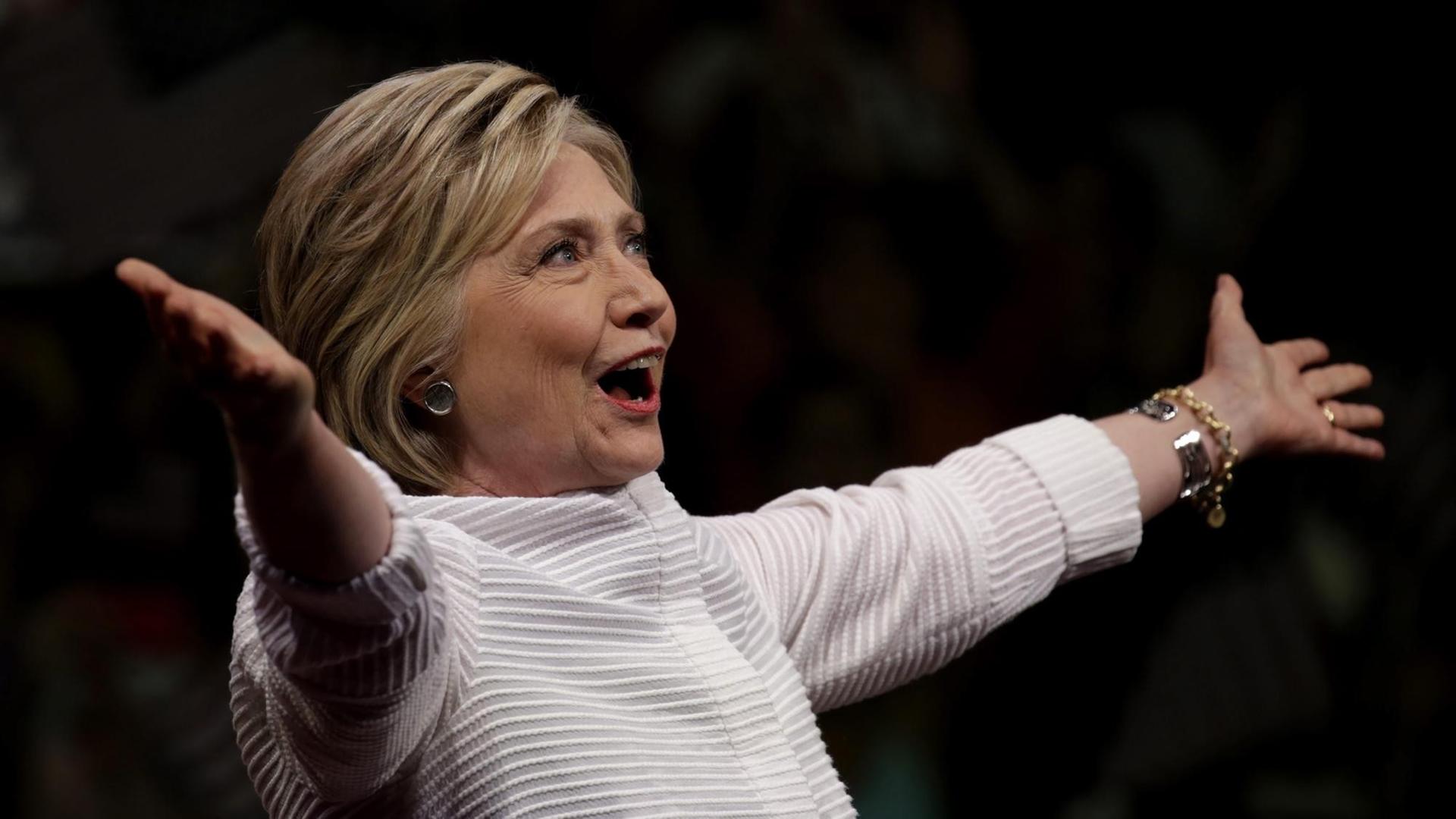 Hillary Clinton breitet die Arme weit aus.