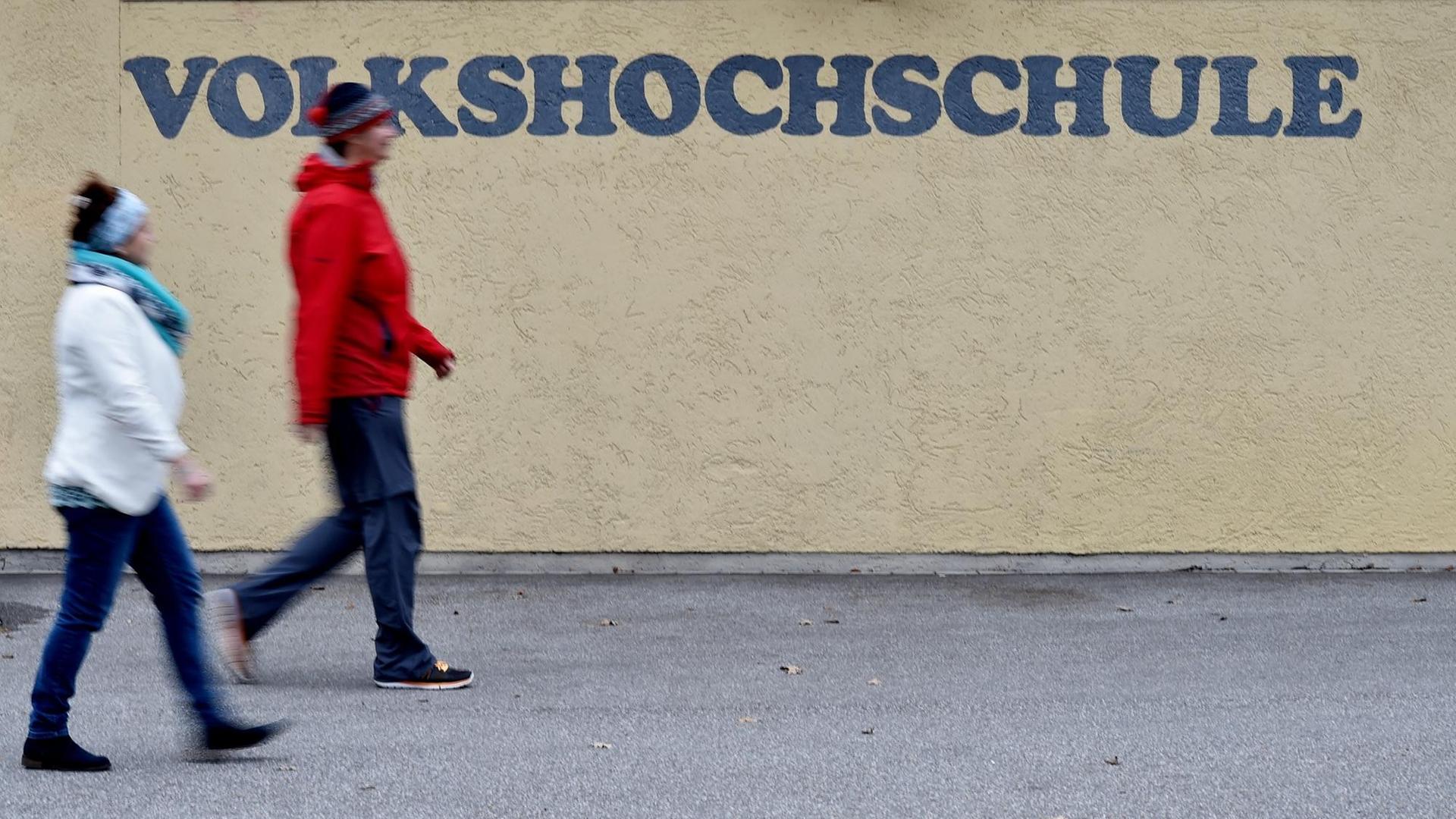 Zwei Frauen gehen in Garmisch-Partenkirchen (Bayern) an einem Schriftzug der Volkshochschule (VHS) vorbei.