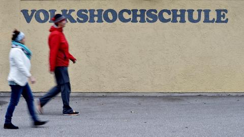 Zwei Frauen gehen in Garmisch-Partenkirchen (Bayern) an einem Schriftzug der Volkshochschule (VHS) vorbei
