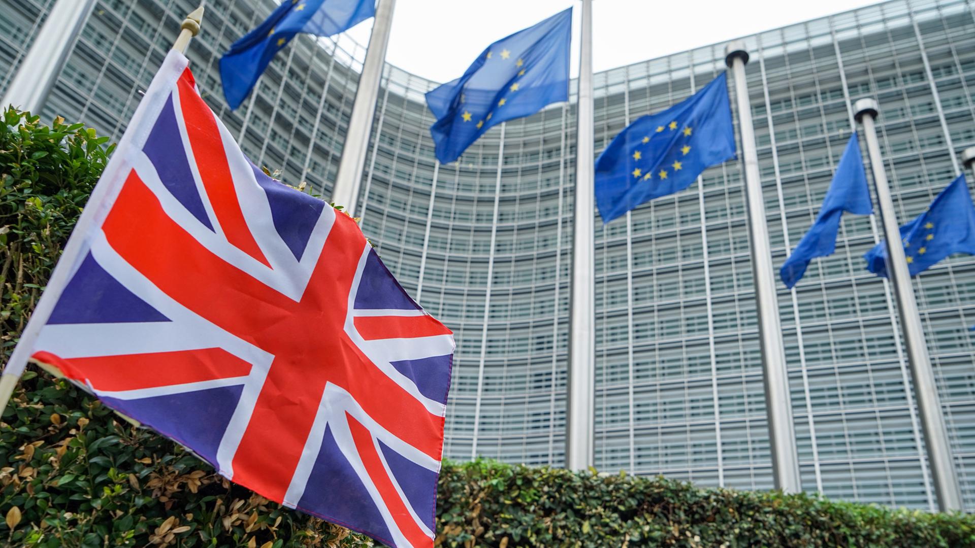 Fahne der EU vor der Europäischen Kommission in Brüssel und eine kleine Fahne Großbritanniens
