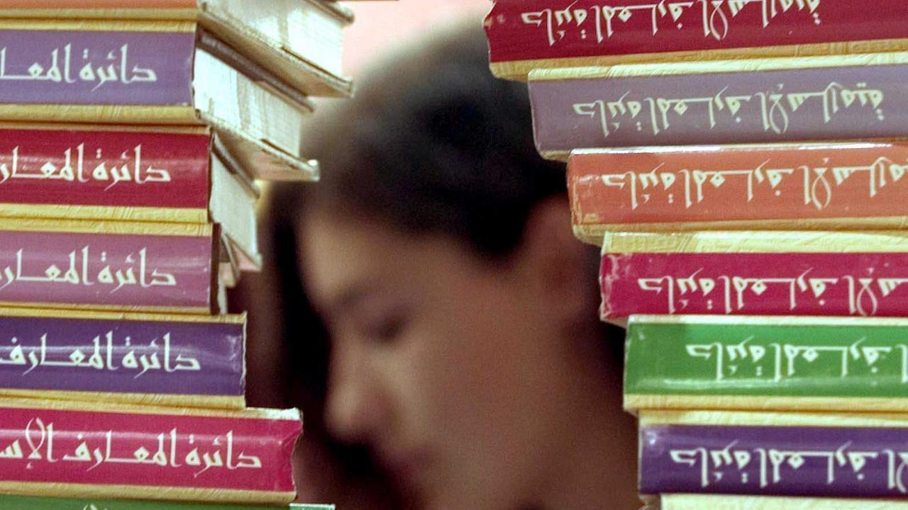 Hinter einer islamischen Enzyklopädie liest eine Besucherin auf der Frankfurter Buchmesse 2004 in der Halle der "Arabischen Welt".