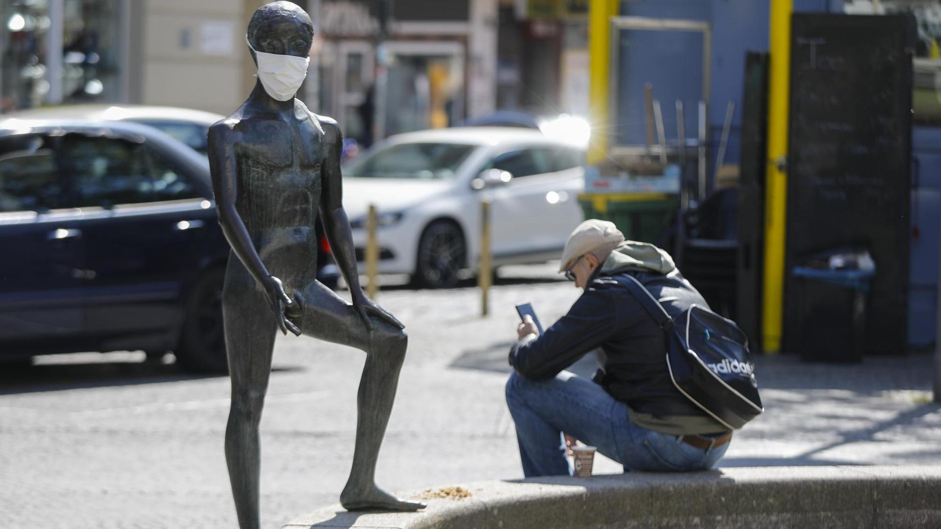 Unbekannte haben einer Figur des Kunstobjekts "Linda mit Schwan, Zyklopen und Zentauer" am Berliner Karl-Marx-Platz mit Mundschutz versehen. Das wegen der Corona Pandemie geltende Kontaktverbot ist um einige Wochen verlängert.