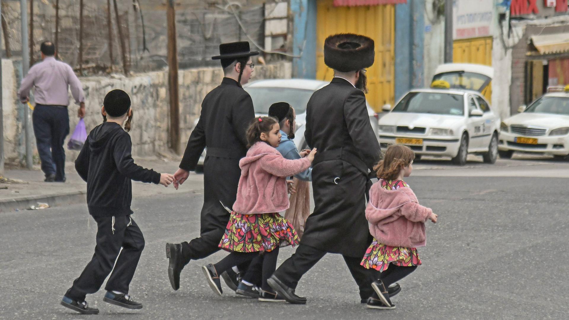 Eine orthodoxe Familie überquert in Jerusalem eine Straße.