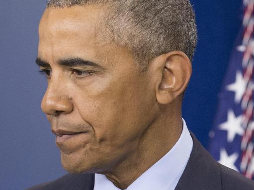 US-Präsident Barack Obama schaut ernst. Er steht vor einer US-Flagge im Weißen Haus.