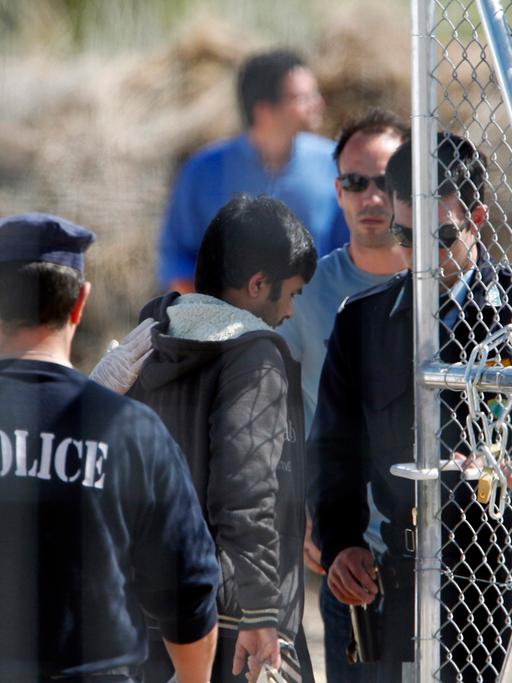 Polizeimänner eskortieren Immigranten zum Einwandererlager in Amygdaleza.