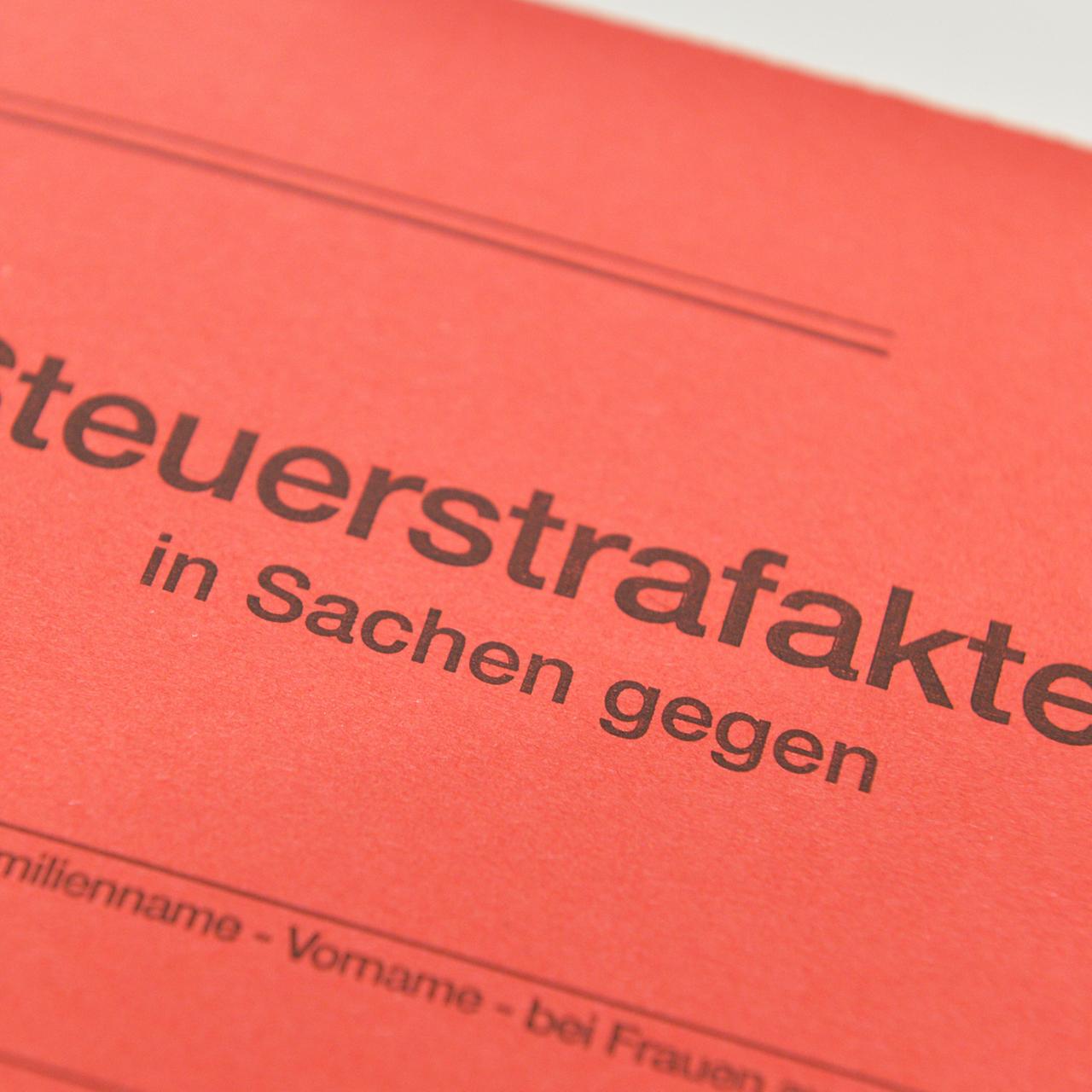 Großaufnahme eines roten Aktendeckels mit der Aufschrift "Steuerstrafakten in Sachen gegen..."