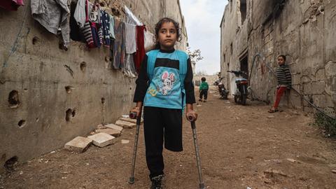 Die neunjährige Fatima Ahmad Mostafa, steht auf einem Bein und einer Krücke in einer Straße in einem Vorort von Idlib in Syrien.