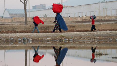 Eine Frau und ihre Kinder tragen in der Provinz Masar-i-Scharif Taschen.