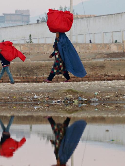 Eine Frau und ihre Kinder tragen in der Provinz Masar-i-Scharif Taschen.