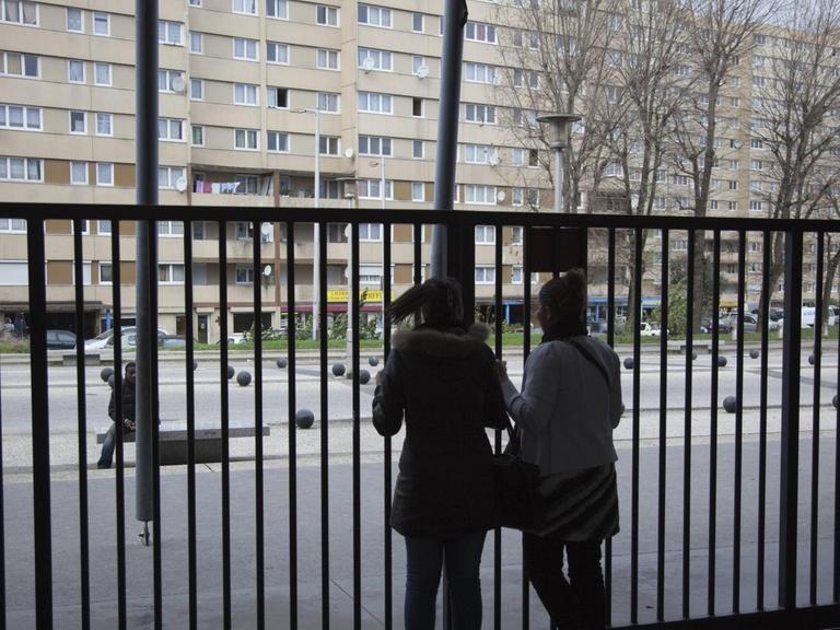 Zwei Schülerinnen am Alfred Nobel Gymnasium im Pariser Vorort Clichy Sous Bois. 2009. Zwei Silhouetten vor einem hohen Zaun, im Hintergrund ein runtergekommener Plattenbau.