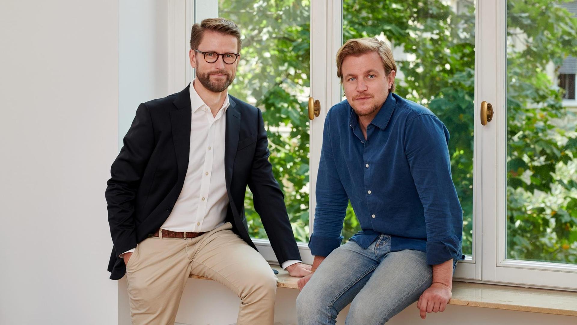 Die zwei Geschäftsführer von Aurora Europe Axel Gille und Philip Schetter stehen vor einem Fenster